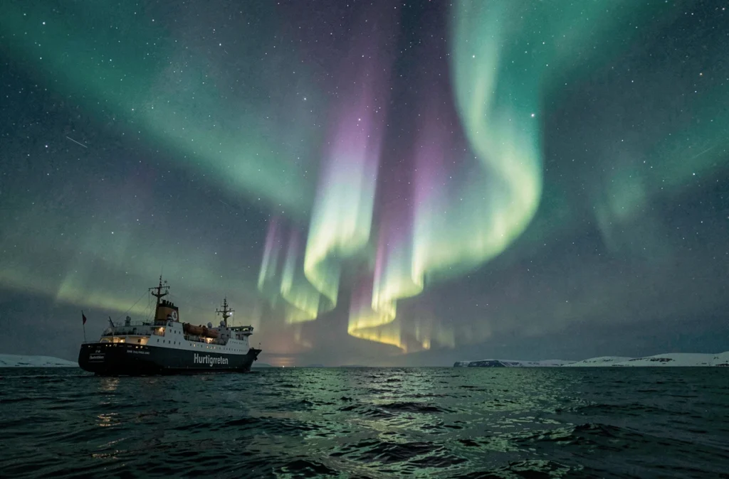 Aurore boréale au-dessus d'un navire Hurtigruten voguant dans les eaux arctiques norvégiennes la nuit