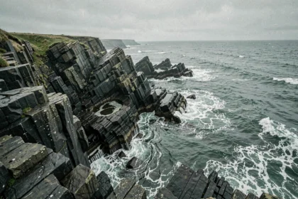 Côte rocheuse sauvage avec falaises de basalte noir et mer agitée au bout du monde
